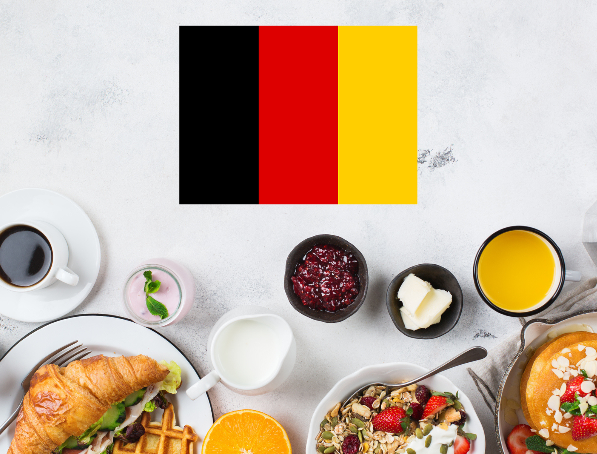 Belgian flag above a breakfast spread with coffee, pastries, fruit, and yogurt on a white table