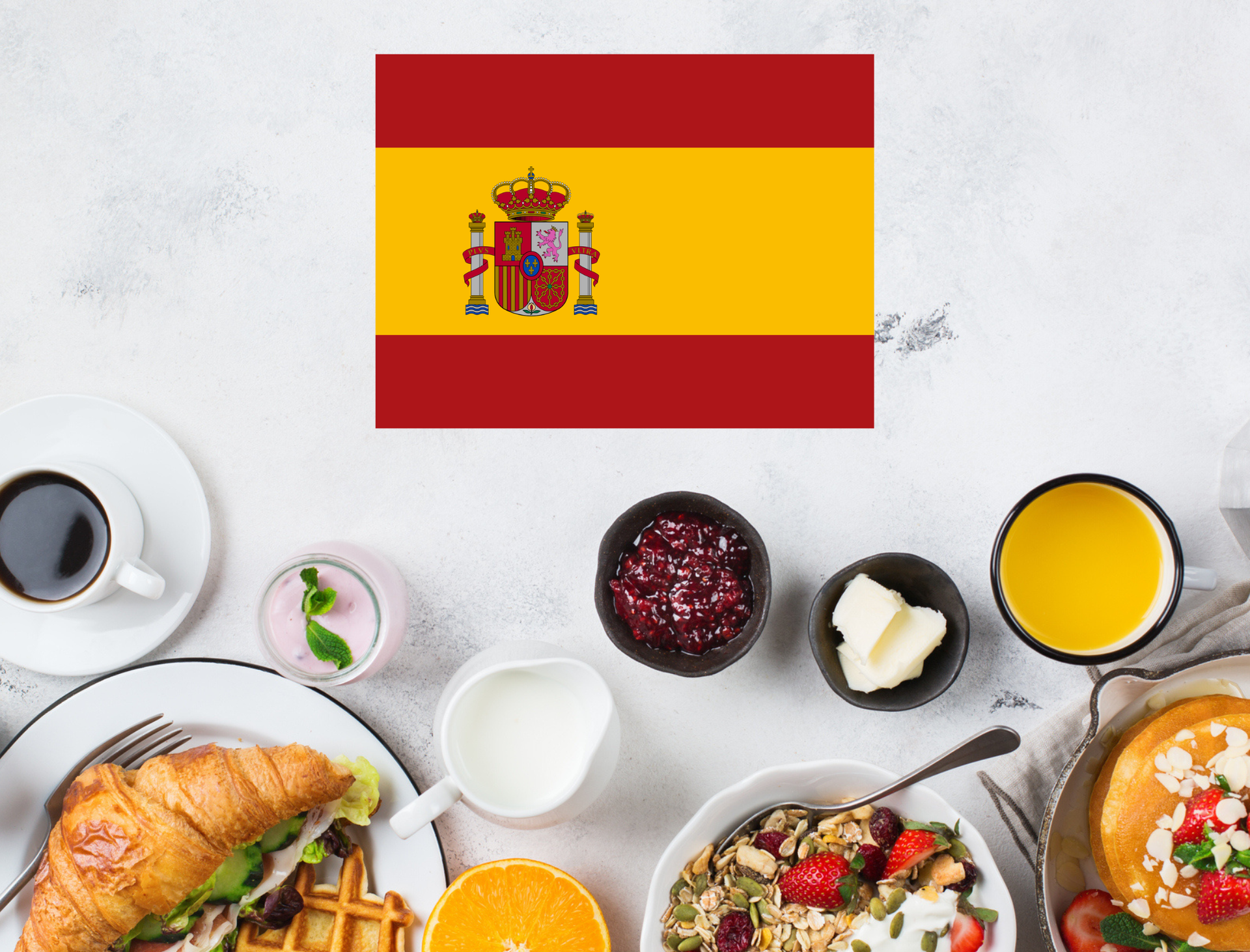 Spanish flag above a breakfast spread with coffee, croissant, fruit, and juice on a white table