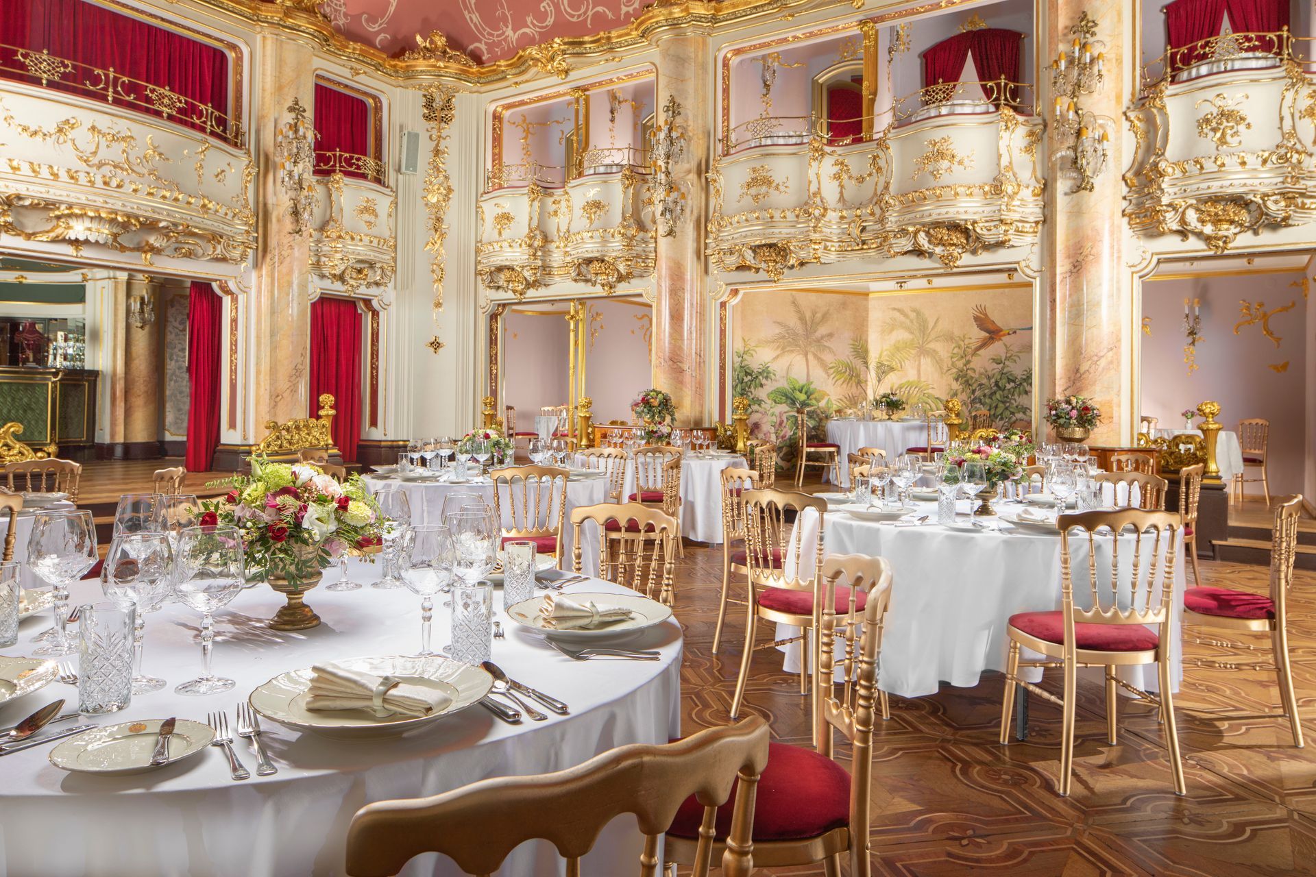 Elegant banquet hall with gold decor, chandeliers, and set tables for a formal event