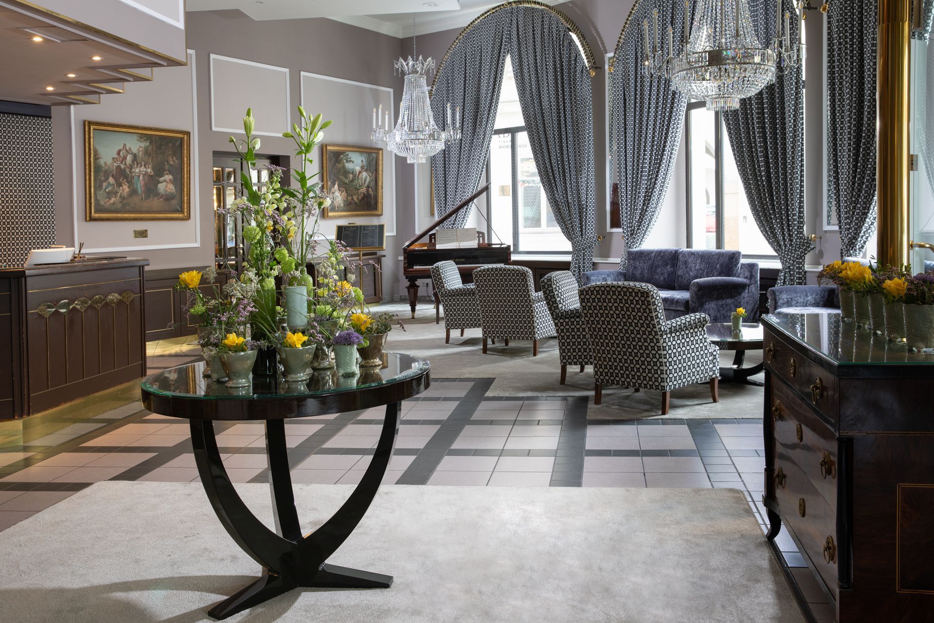 Elegant hotel lobby with patterned chairs, tall windows, and a floral table centerpiece