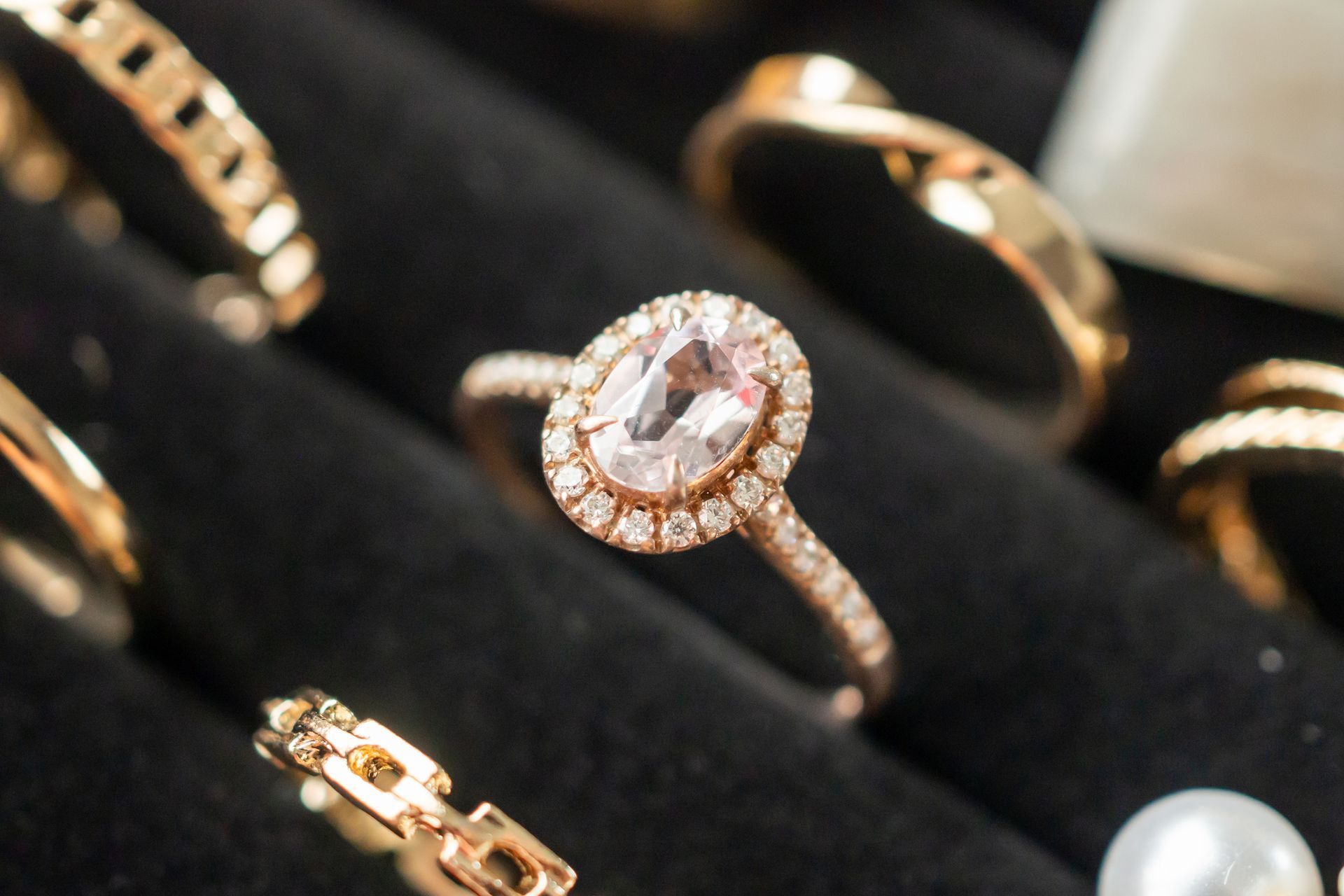 Gold jewelry, including rings, necklaces, and a wristwatch, lies on a rough surface.