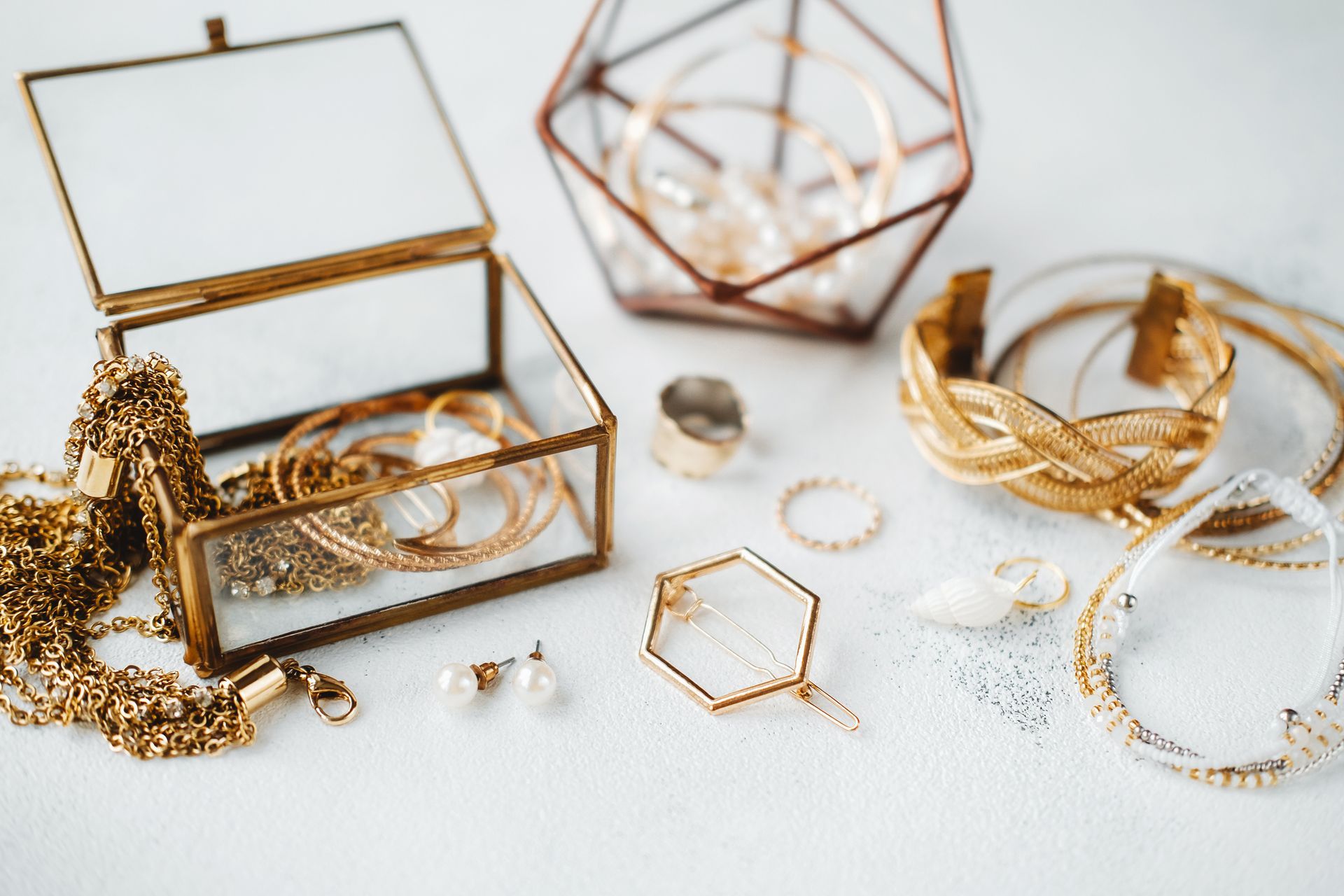 Golden jewelry displayed on a white surface, including bracelets, rings, necklaces, and earrings.