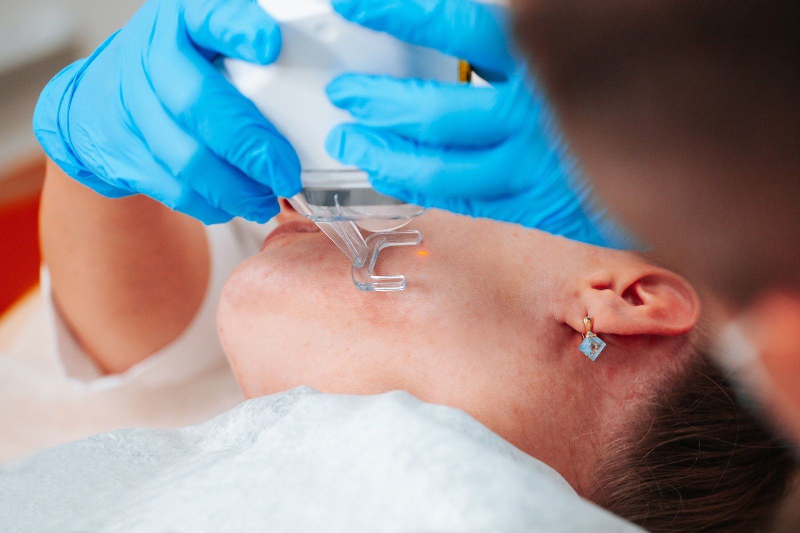 Gloved hands applying a dental tool to a patient’s open mouth during an oral exam