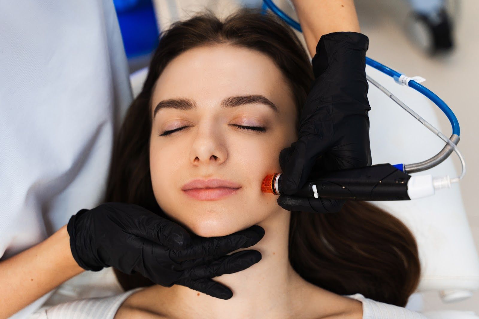 Cosmetic treatment with a gloved practitioner using a handheld device on a relaxed client’s face