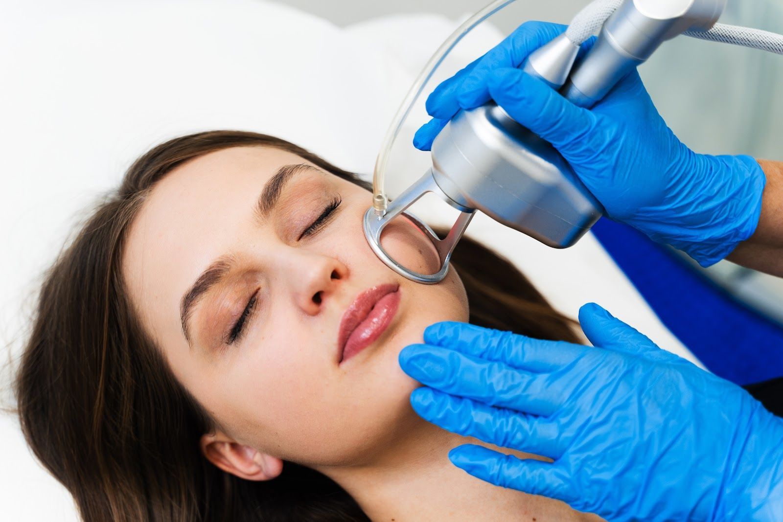 Cosmetic treatment being applied to a woman’s chin with a handheld device and gloved hands