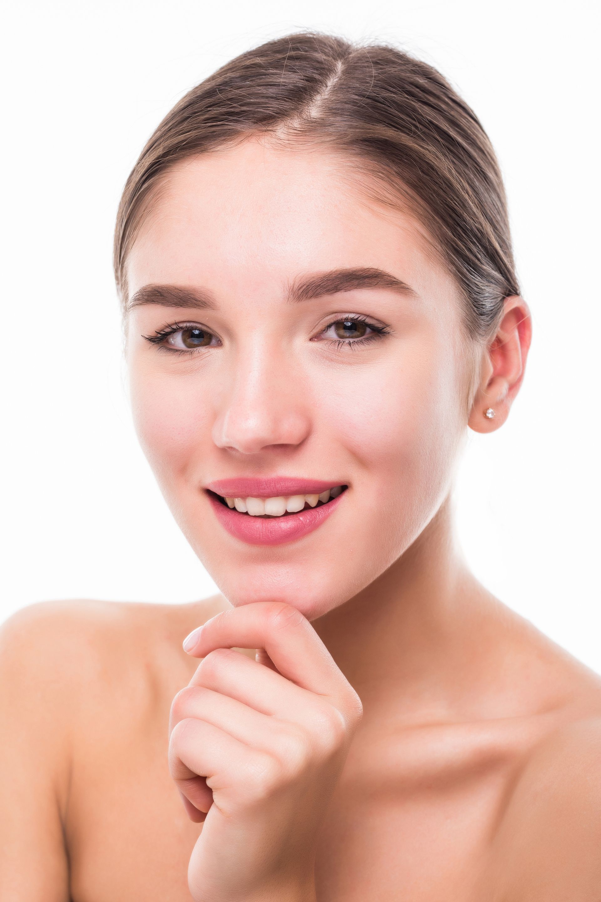 Smiling woman with bare shoulders, resting her chin on her hand against a white background