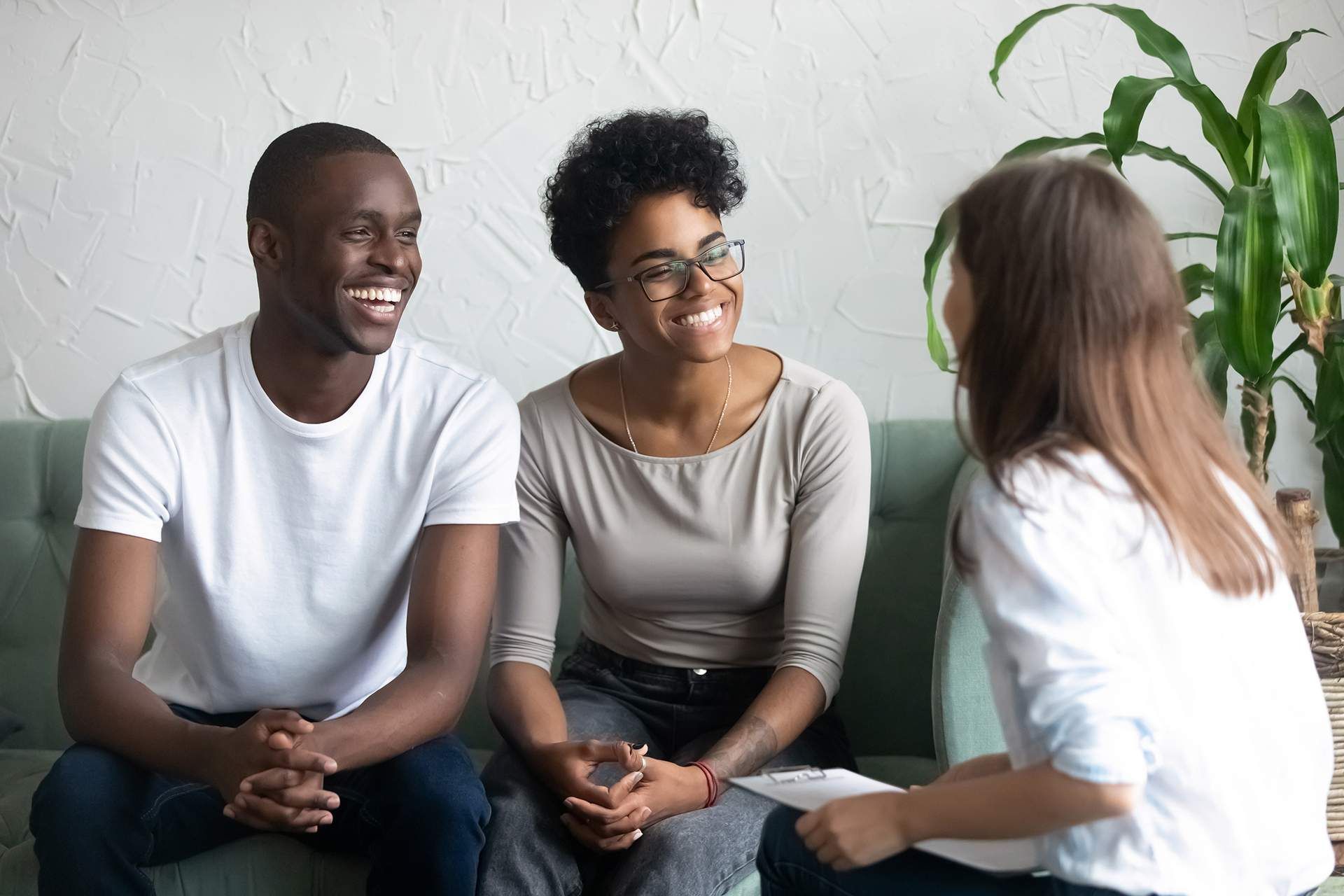 Three people talking and smiling on a couch in a bright living room