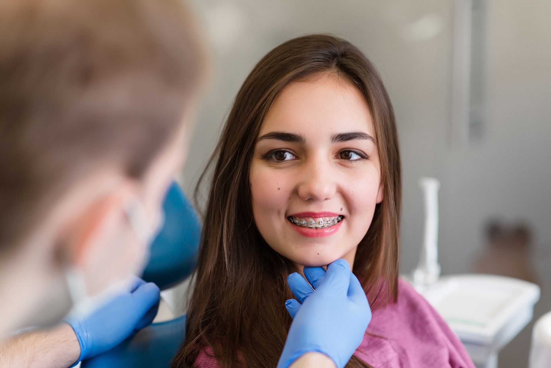 Dentist examining a smiling patient with braces in a clinic