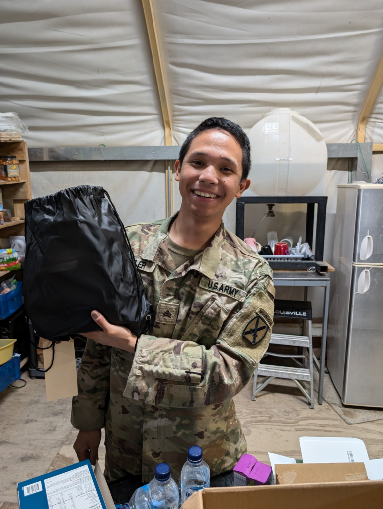 Soldier in uniform smiling, holding black bag