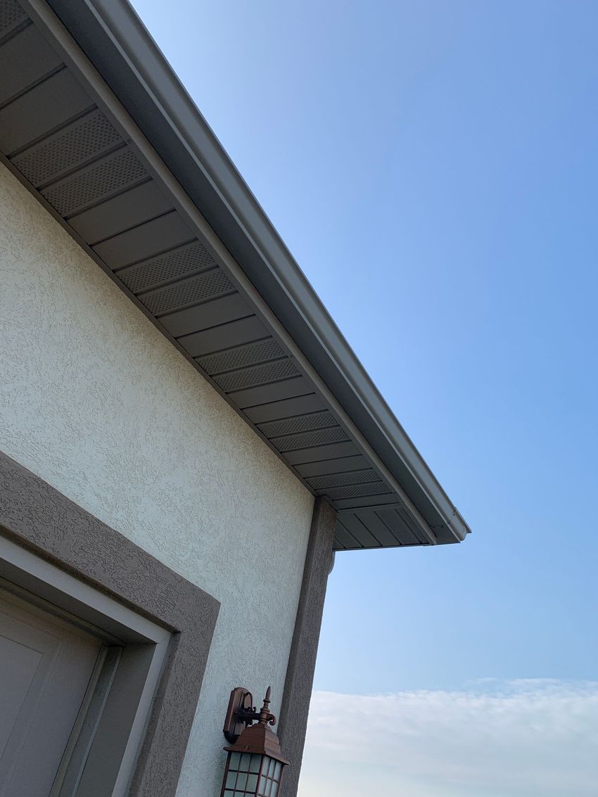 House exterior with gray roof trim and a wall-mounted security camera against a blue sky
