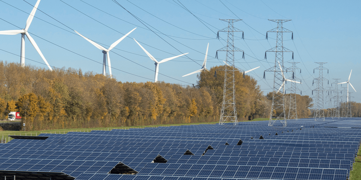 Solar panels, wind turbines, and power lines on a sunny day, showcasing renewable energy sources.