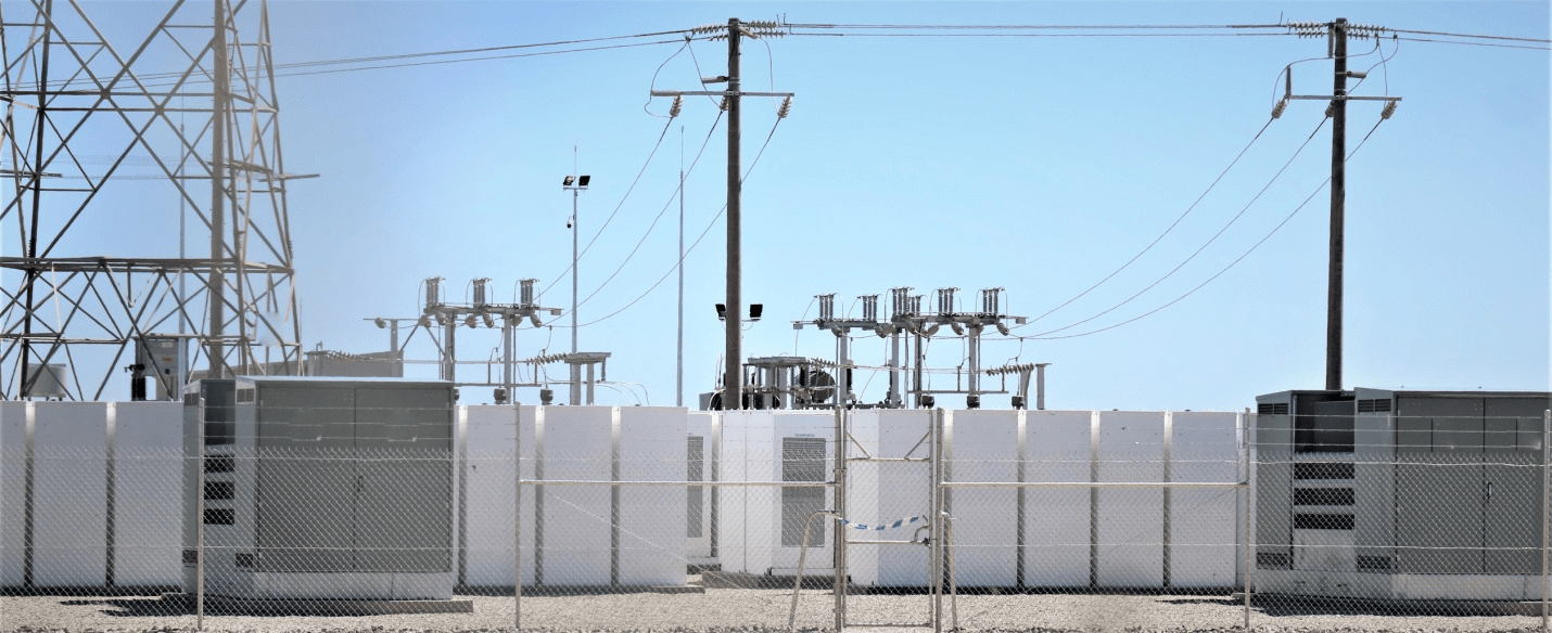 Power plant with transformers, high voltage power lines, and clear blue sky.