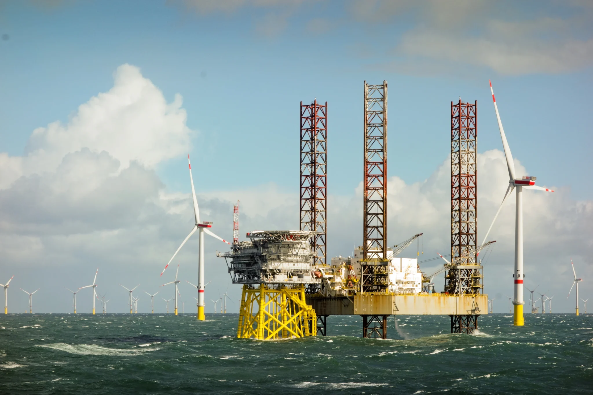 Offshore wind turbines and a maintenance platform in the ocean, yellow support legs.
