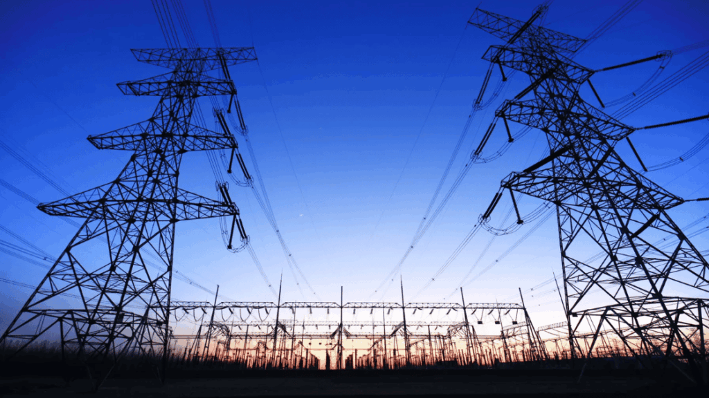 Silhouetted power lines and towers against a blue twilight sky.