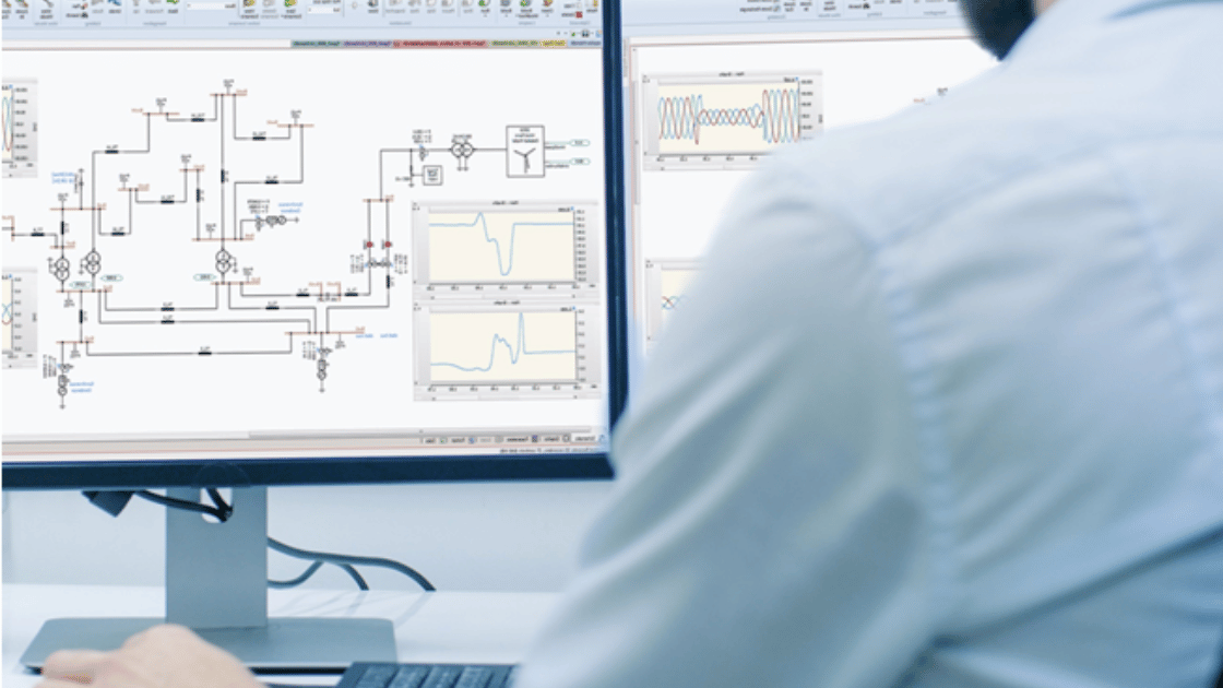 Person looking at two computer monitors displaying technical diagrams and graphs.