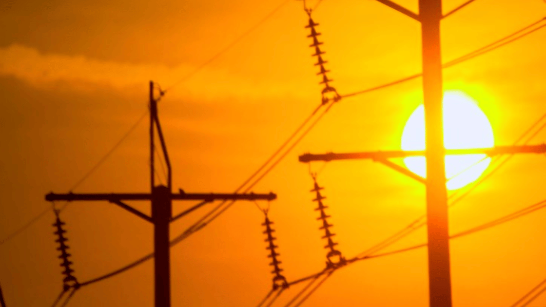 Silhouette of power lines against a vibrant orange sunset.
