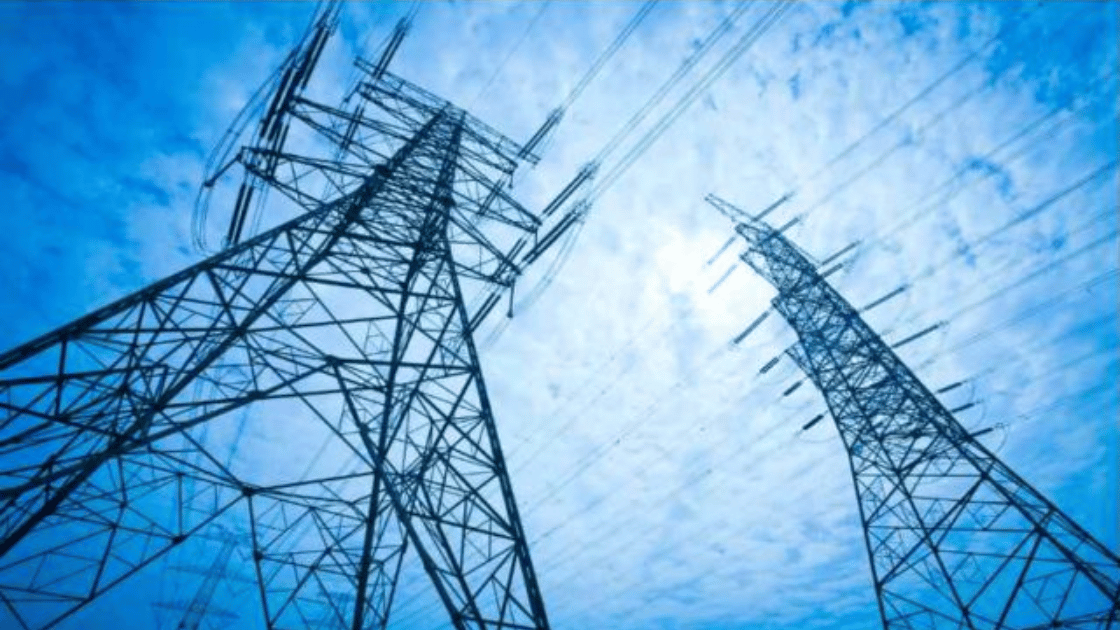 Two tall power line towers against a bright blue sky with power lines strung between them.