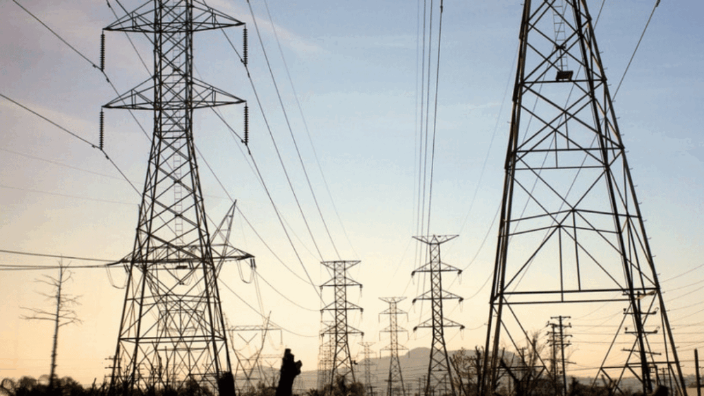 Power lines and towers against a light blue and yellow sky.