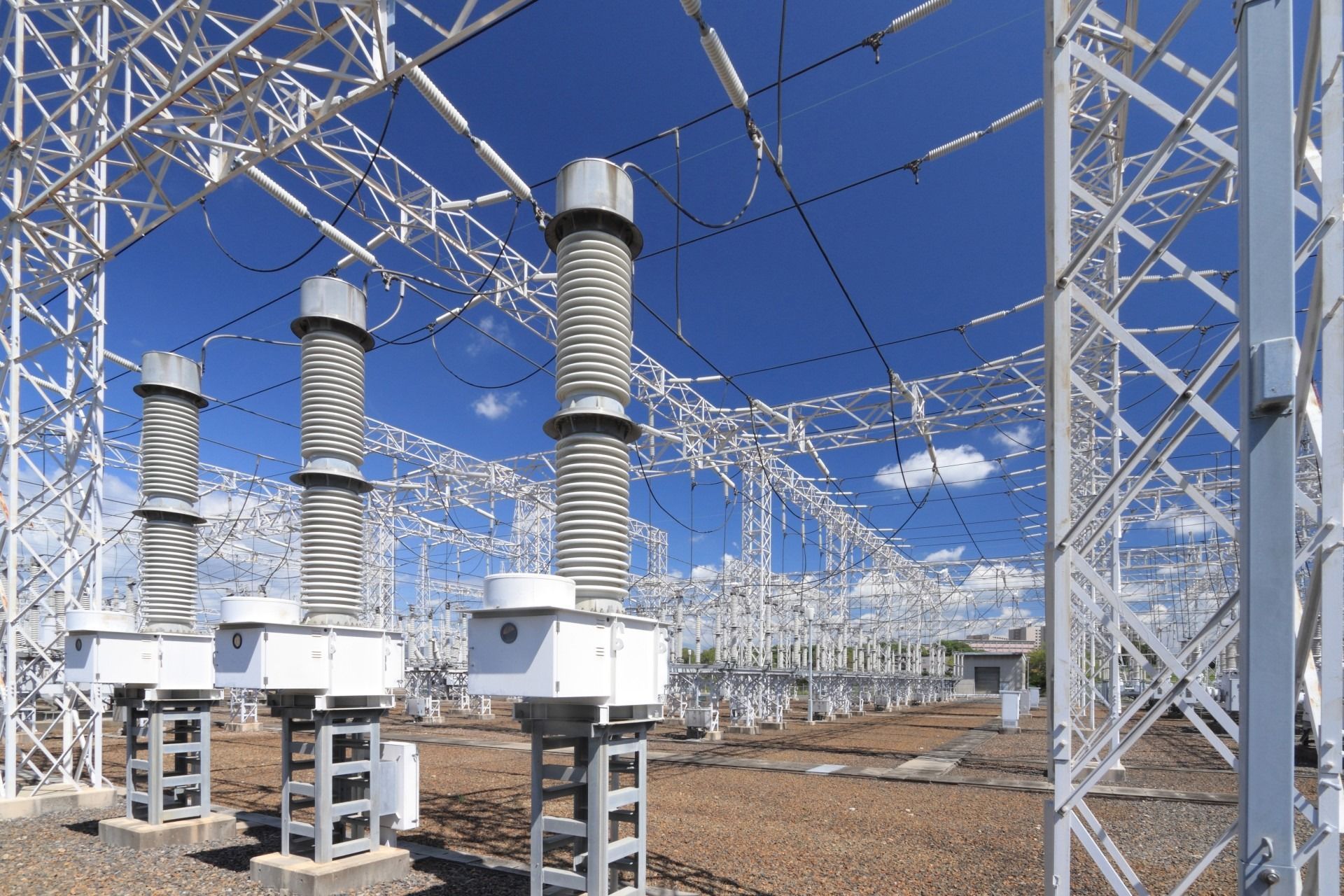Electrical substation with tall insulators, metal framework, and a blue sky.