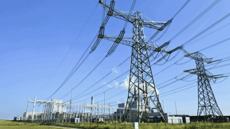 High voltage power lines and towers against a blue sky, connecting to a power substation.