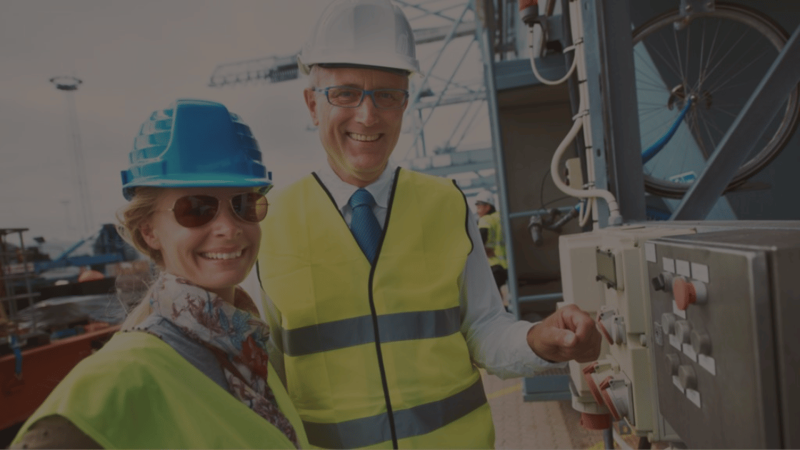 Two construction workers in safety vests and hard hats operating machinery.