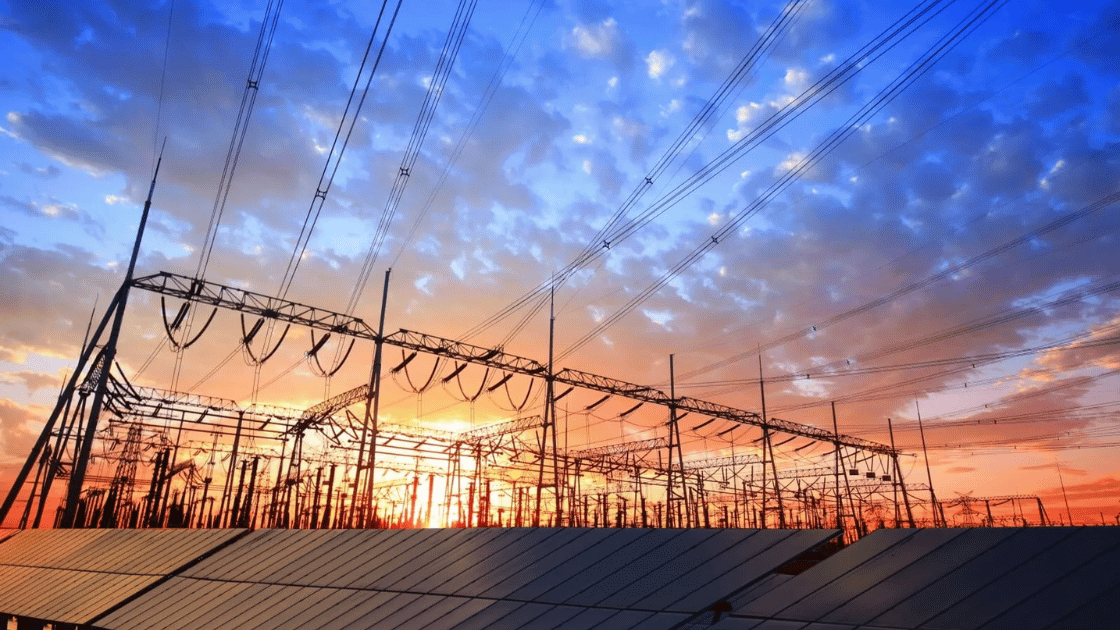 Power lines over a substation at sunset with colorful clouds.