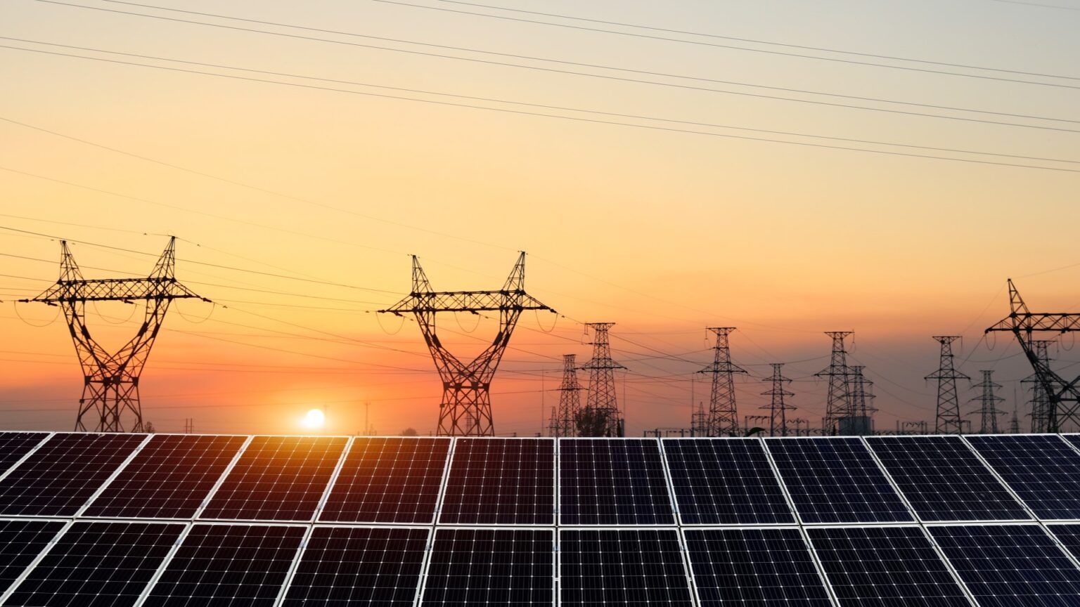 Solar panels with power lines at sunset.