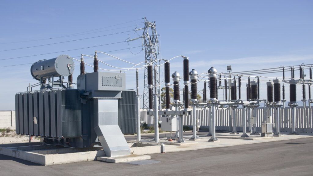 Electrical transformer and power distribution equipment in outdoor setting. Gray metal with blue sky.