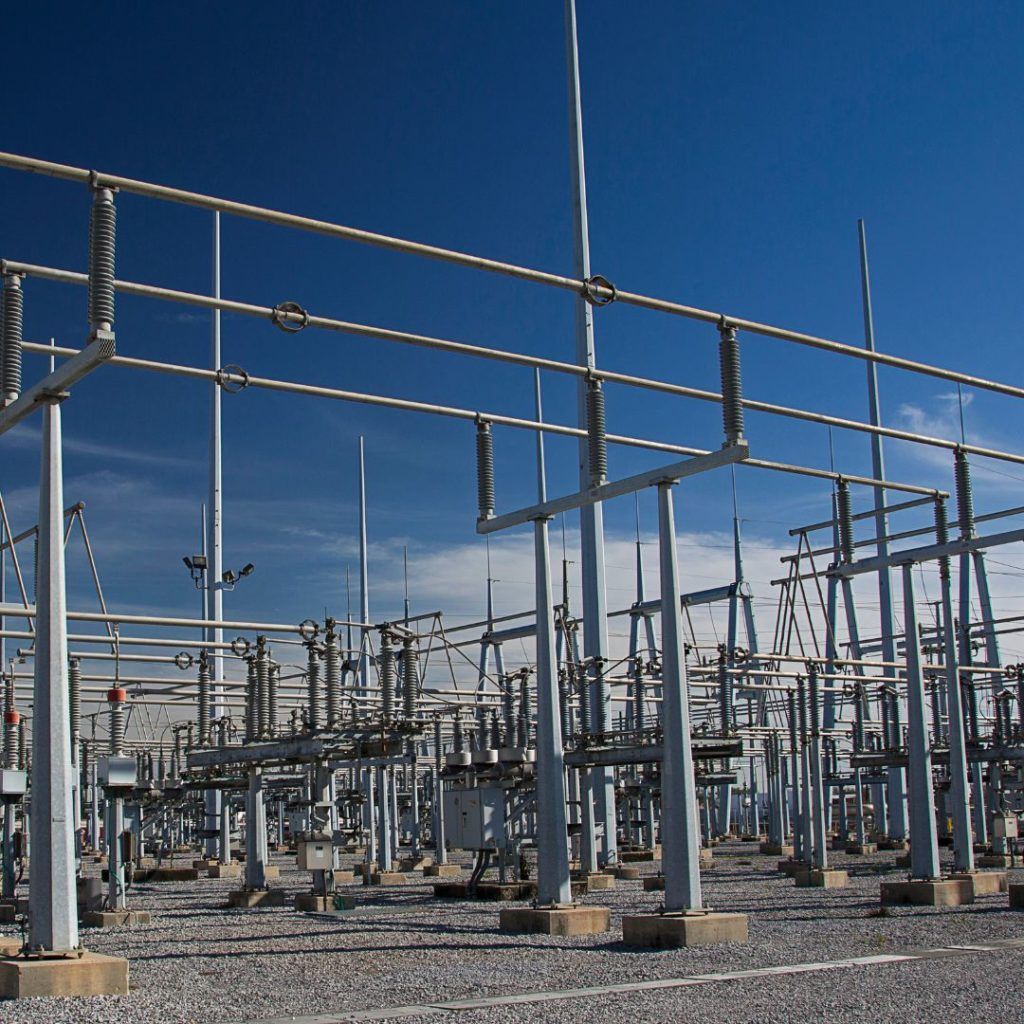 Electrical substation against a clear blue sky, with metal structures and power lines.
