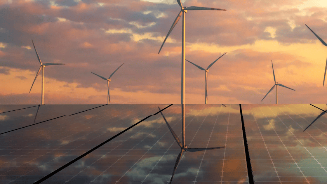 Solar panels in foreground, wind turbines in background, sunset sky with orange hues.