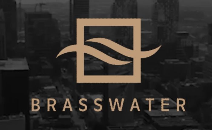 Plumber in blue hard hat uses wrench on pipes in a utility room.