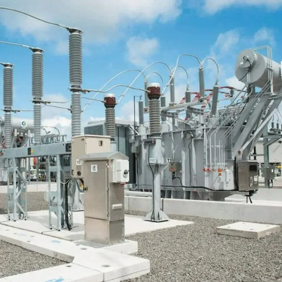 Electrical substation with transformers, insulators, and wiring against a blue sky.