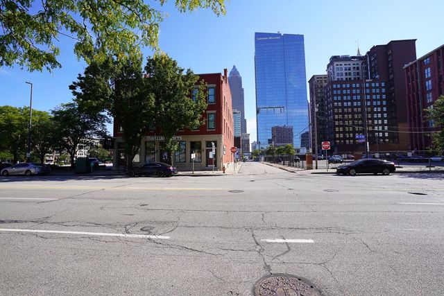 Quiet city intersection with a tall blue glass skyscraper and surrounding brick buildings under a clear sky