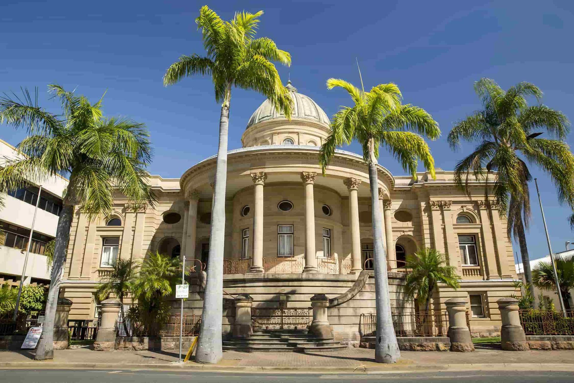 A Large Building With Palm Trees In Front Of It — CQ Service Locating In Rockhampton, QLD