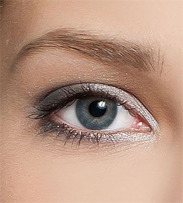 Close-up of a blue eye with silver eyeshadow and groomed eyebrow.