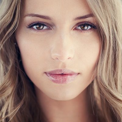 Woman with light brown hair, brown eyes, and light pink lipstick looking at the camera.