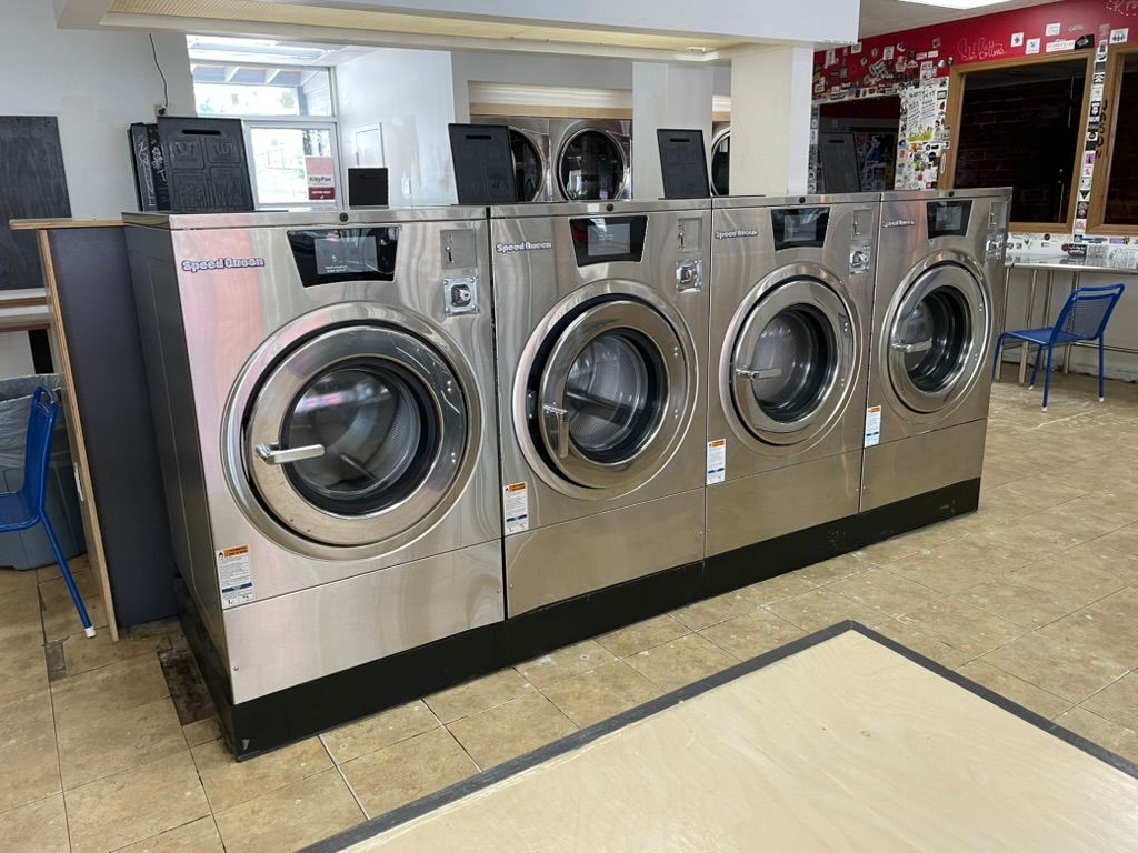 A row of washing machines are lined up in a laundromat.