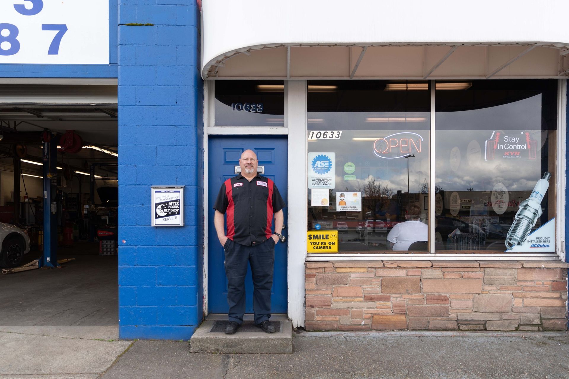 Technician in front of front door of our shop with after hours key drop off in Seattle, WA | Masters Auto & Tire