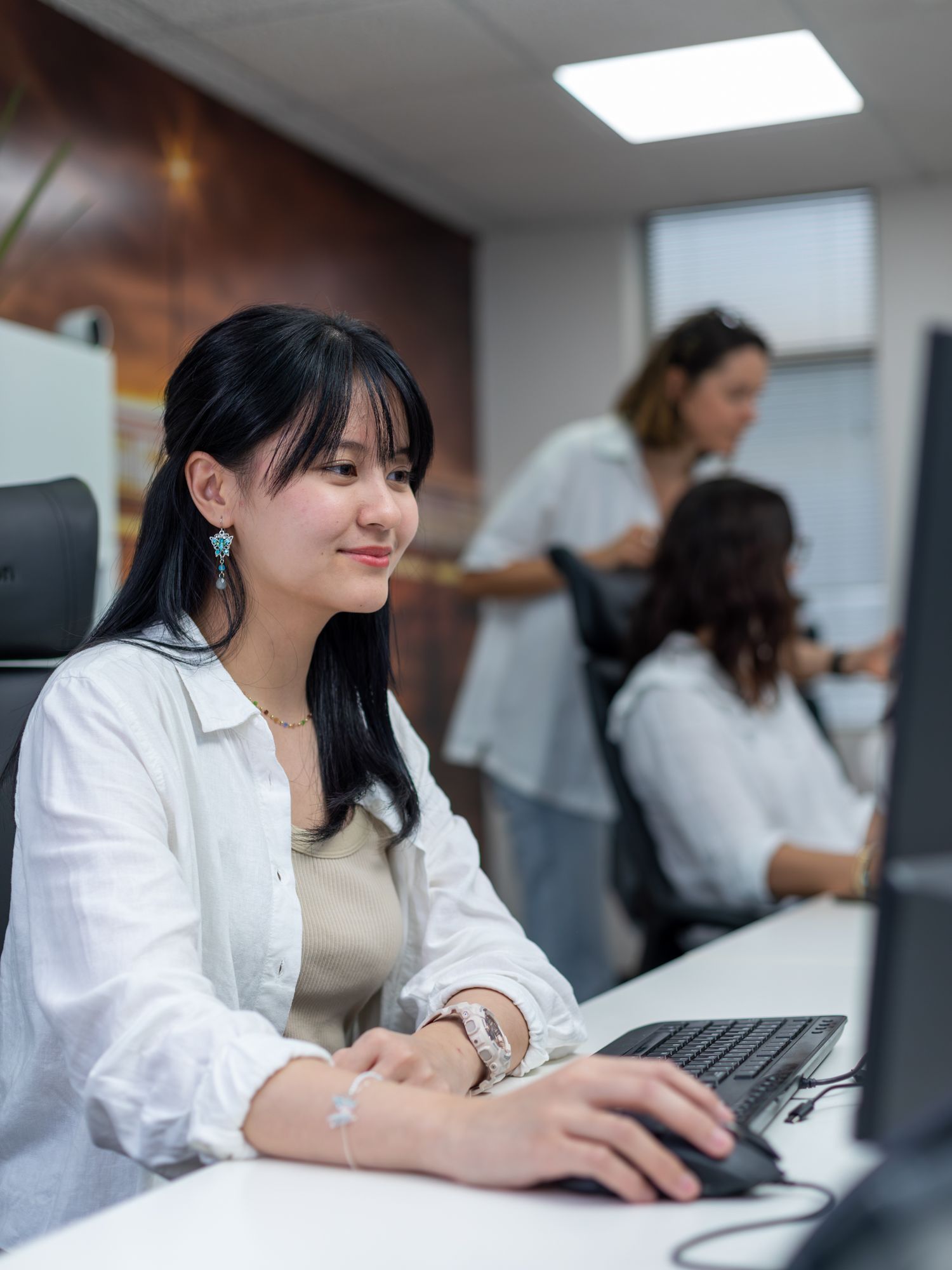 A woman is sitting at a desk in front of a computer.