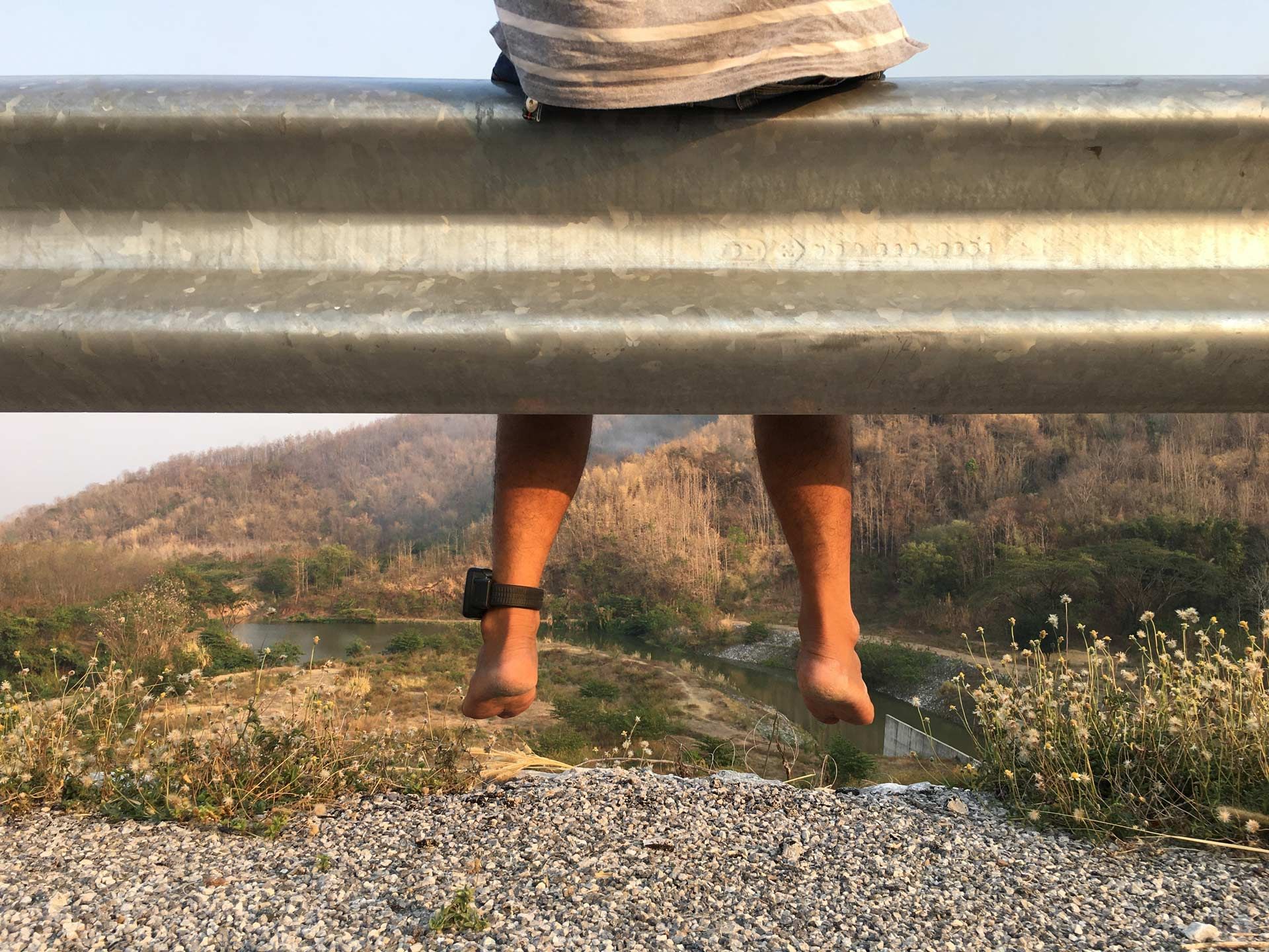 A person 's feet are sticking out from under a metal railing