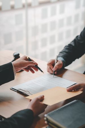 Two people are sitting at a table signing a document