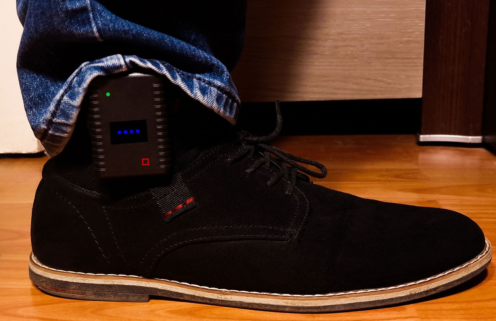 A person is wearing a black shoe with a small device attached to it
