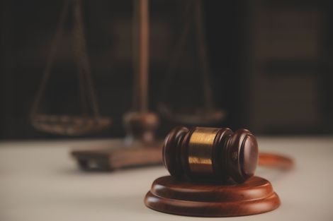 A judge 's gavel is sitting on a wooden base in front of a scale of justice