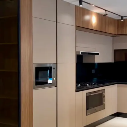 Cuisine moderne avec placards beige clair, appareils électroménagers en acier inoxydable et plans de travail foncés.