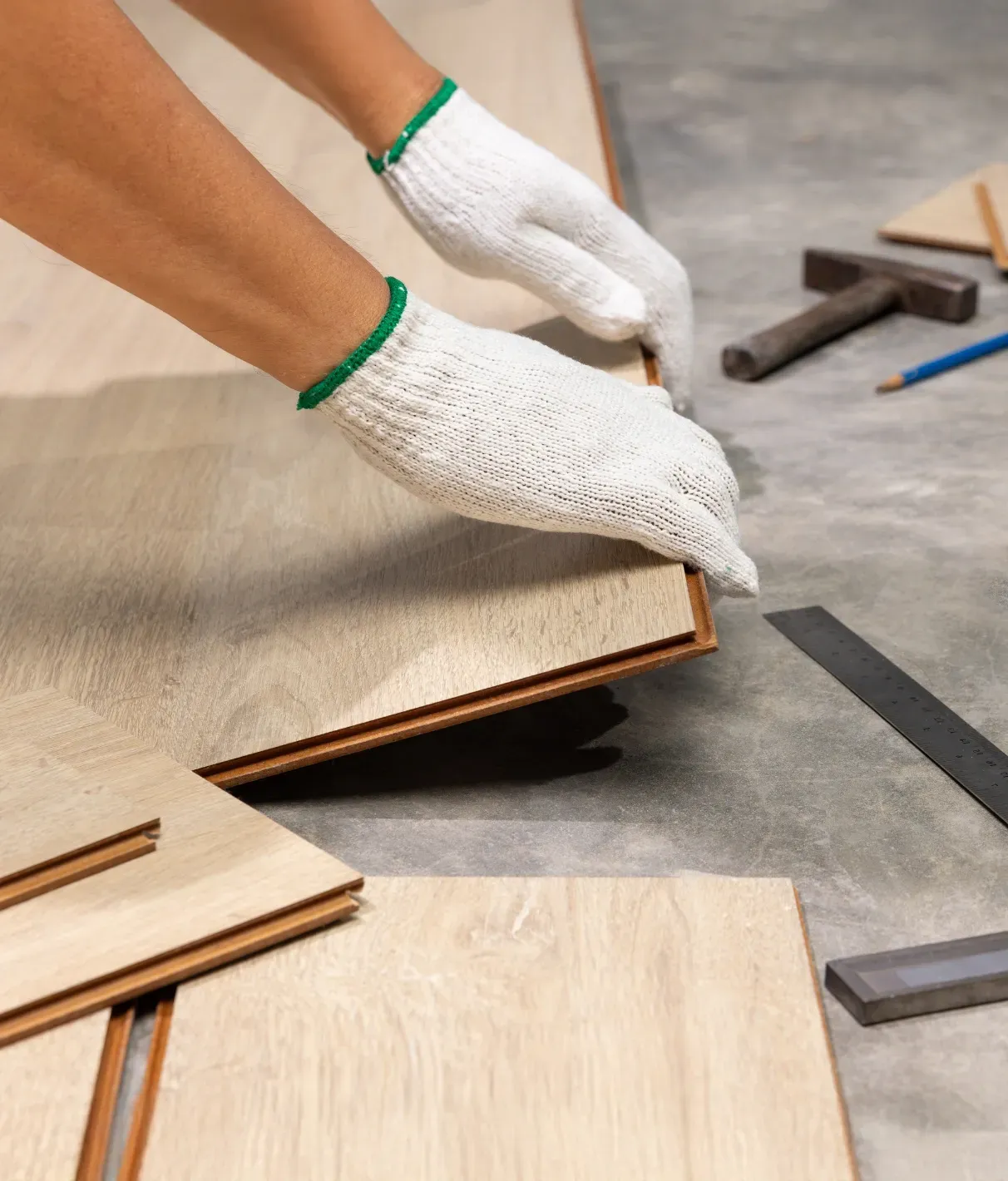 Des mains gantées de blanc posent des lames de parquet.
