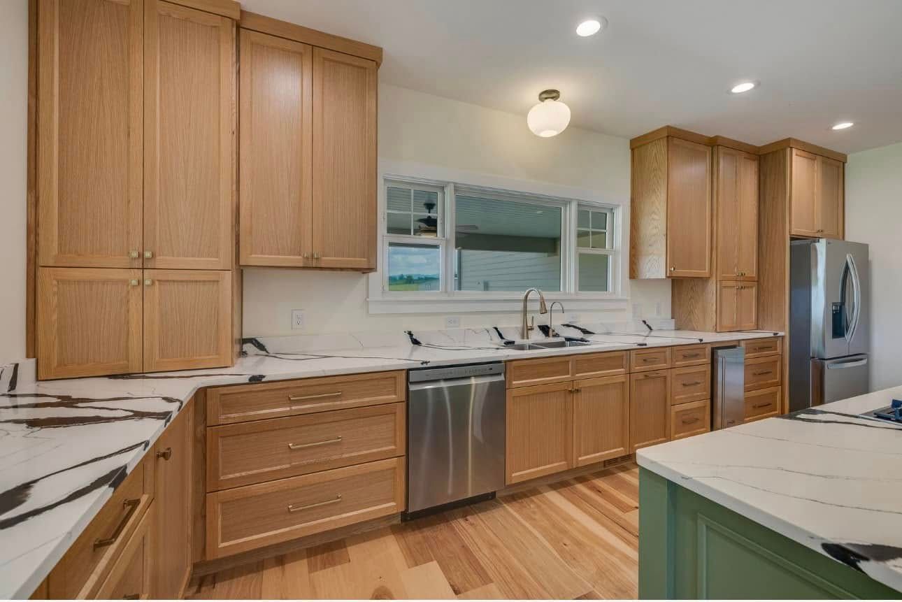 Bright kitchen with wood cabinets, white countertops, stainless appliances, and a window above the sink