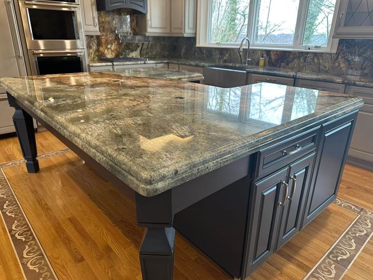 Granite kitchen island with dark wood base and built-in cabinets on a hardwood floor