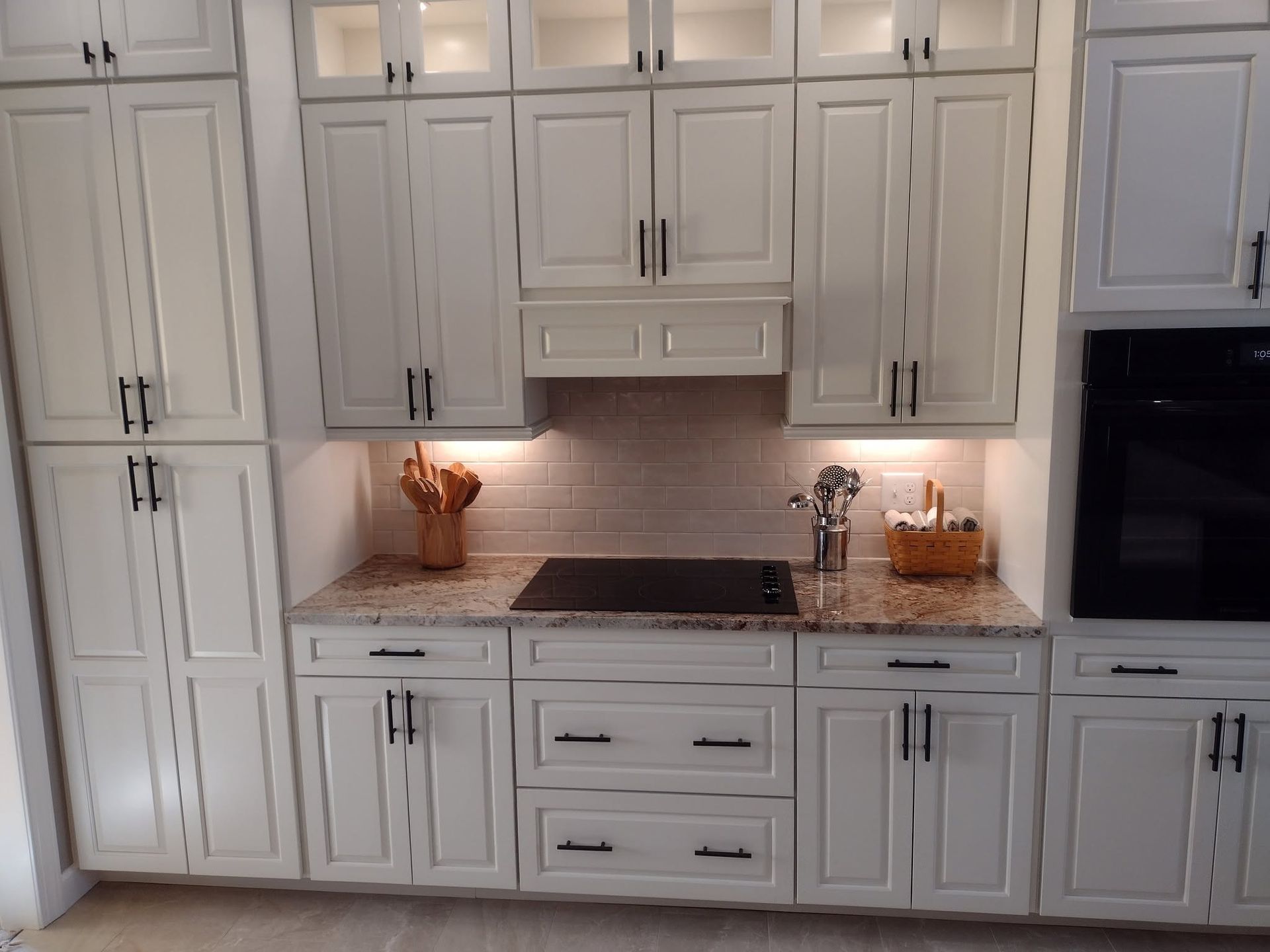 White kitchen with cabinets, granite countertops, built-in oven, and decorative items on the counter.