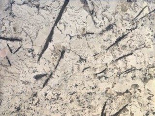 Close-up of a pale stone or concrete surface with dark cracks and streaks