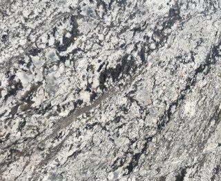 Close-up of rough gray-white rock with dark streaks and speckled texture